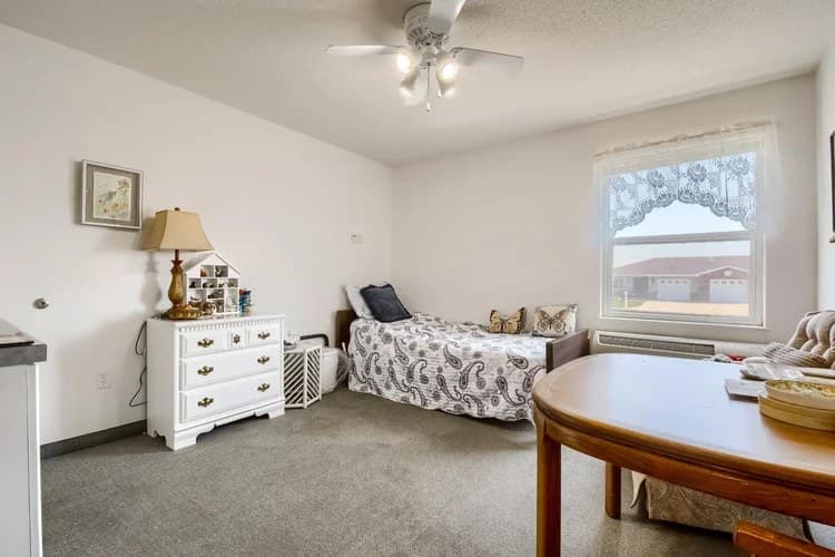 Private resident bedroom with window, dresser, and seating at Aspen Leaf 6th Street