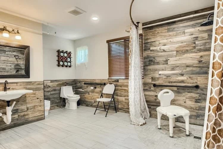Accessible resident bathroom with roll-in shower, grab bars, and shower chair at Aspen Leaf Circle Lane
