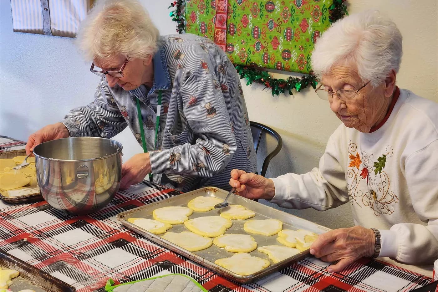 Residents rolling and cutting sugar cookies at a kitchen table at Aspen Leaf