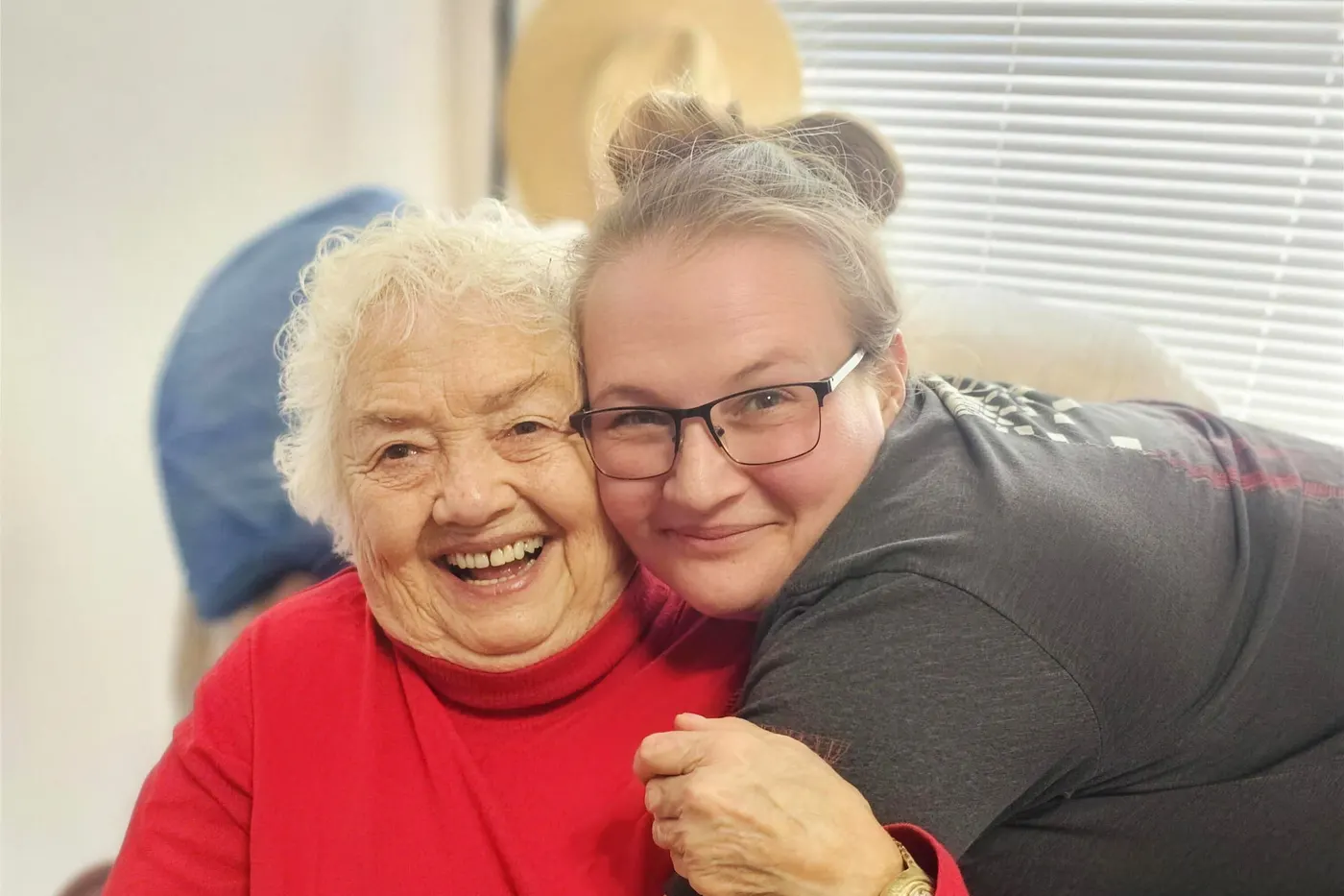 A resident and her caregiver with their arms around each other at an Aspen Leaf home