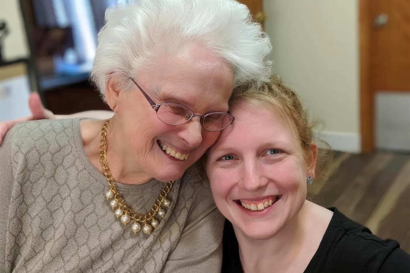 A resident and a member of the Aspen Leaf team smiling together, cheek to cheek