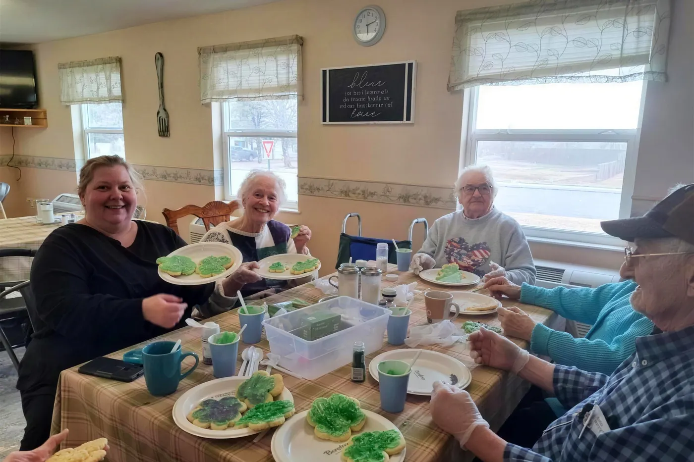 Residents and staff decorating cookies together around a sunlit dining table at Aspen Leaf