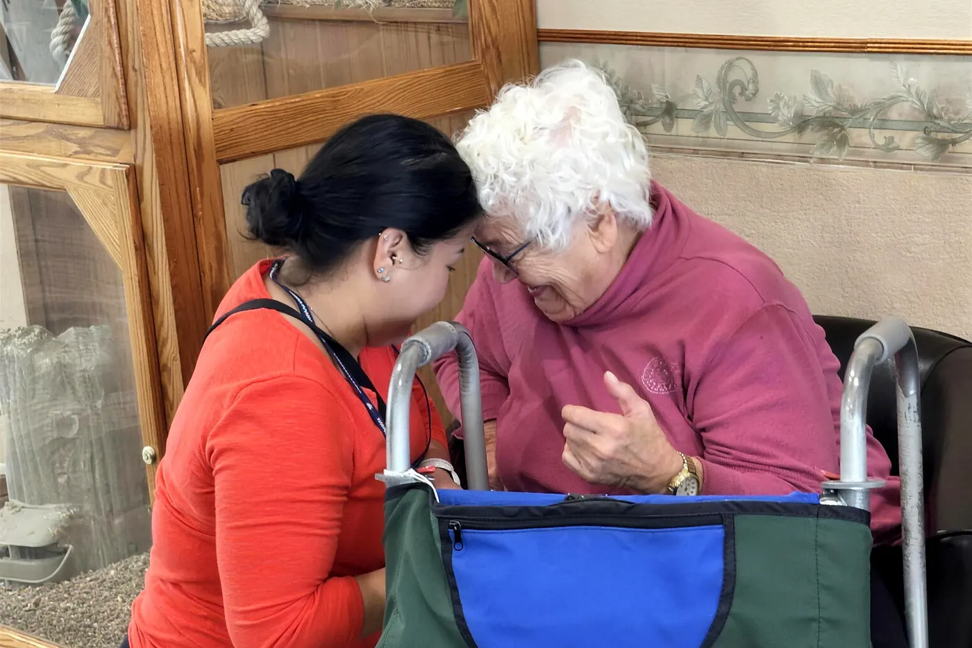 A caregiver leaning in to talk with a resident at eye level in an Aspen Leaf home