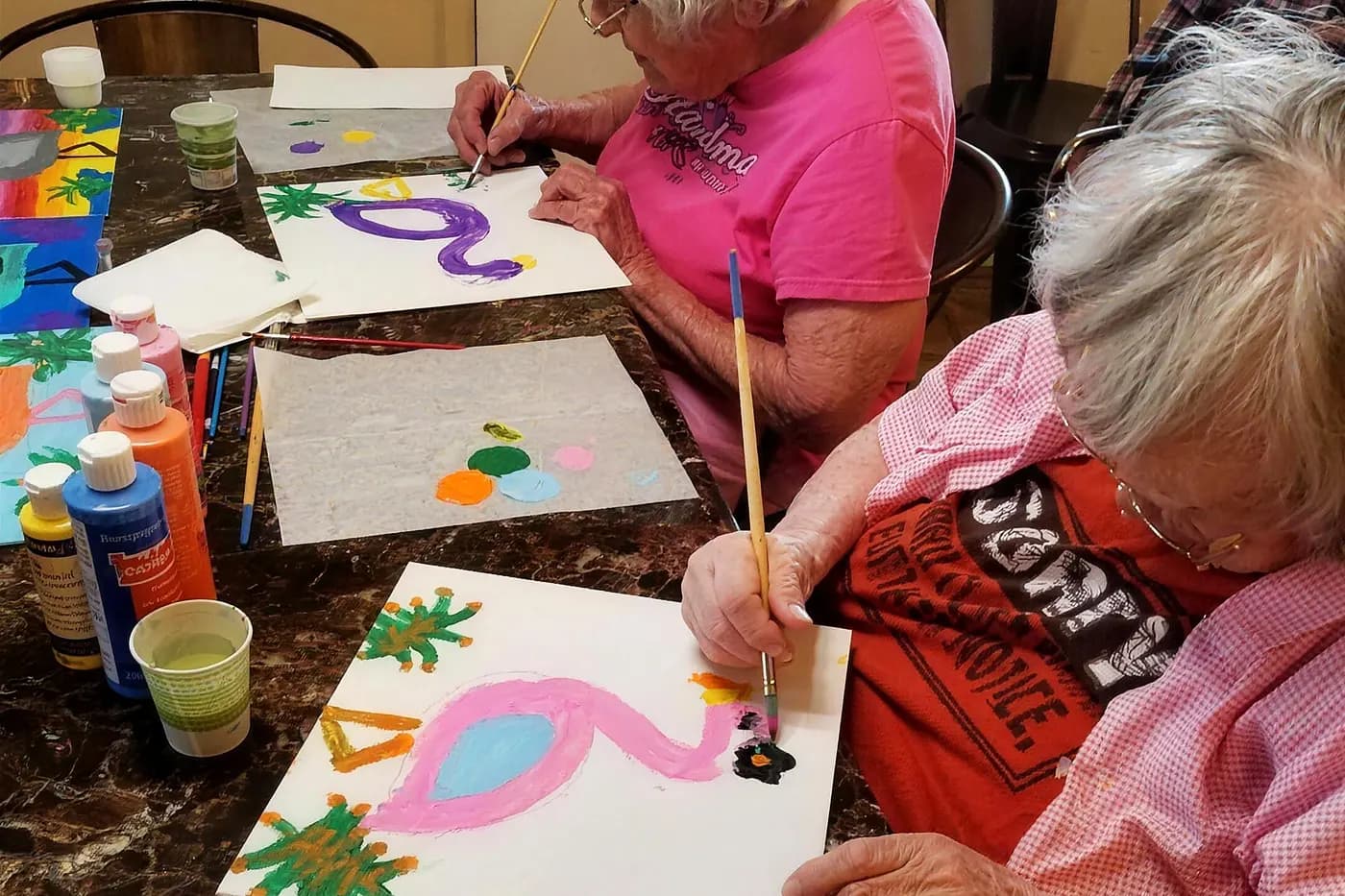 Residents painting canvases together at the craft table in an Aspen Leaf home