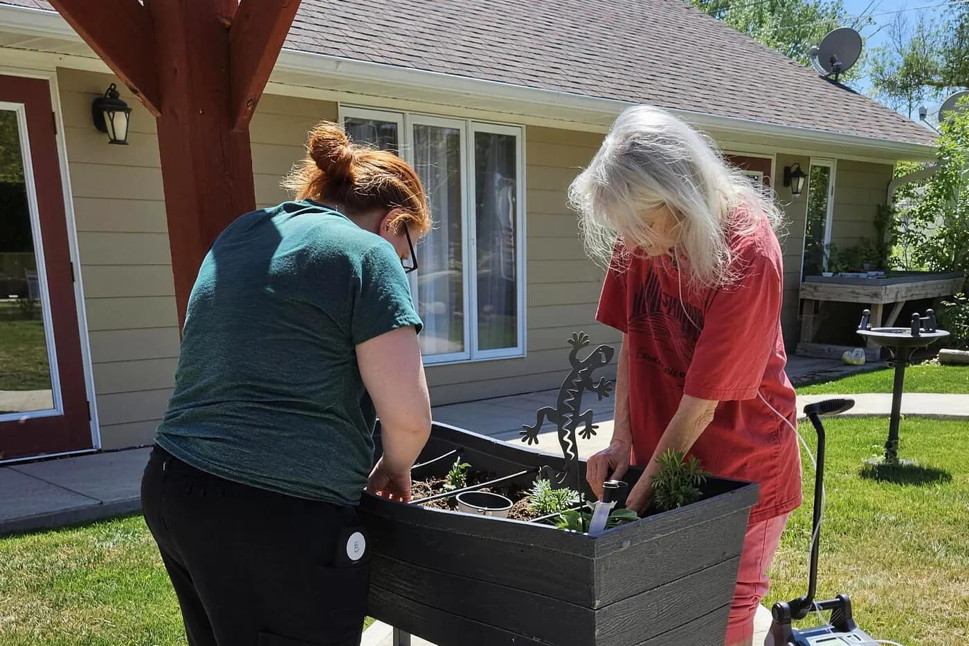 A resident and a caregiver planting the raised garden beds under the pergola at Aspen Leaf Flagler