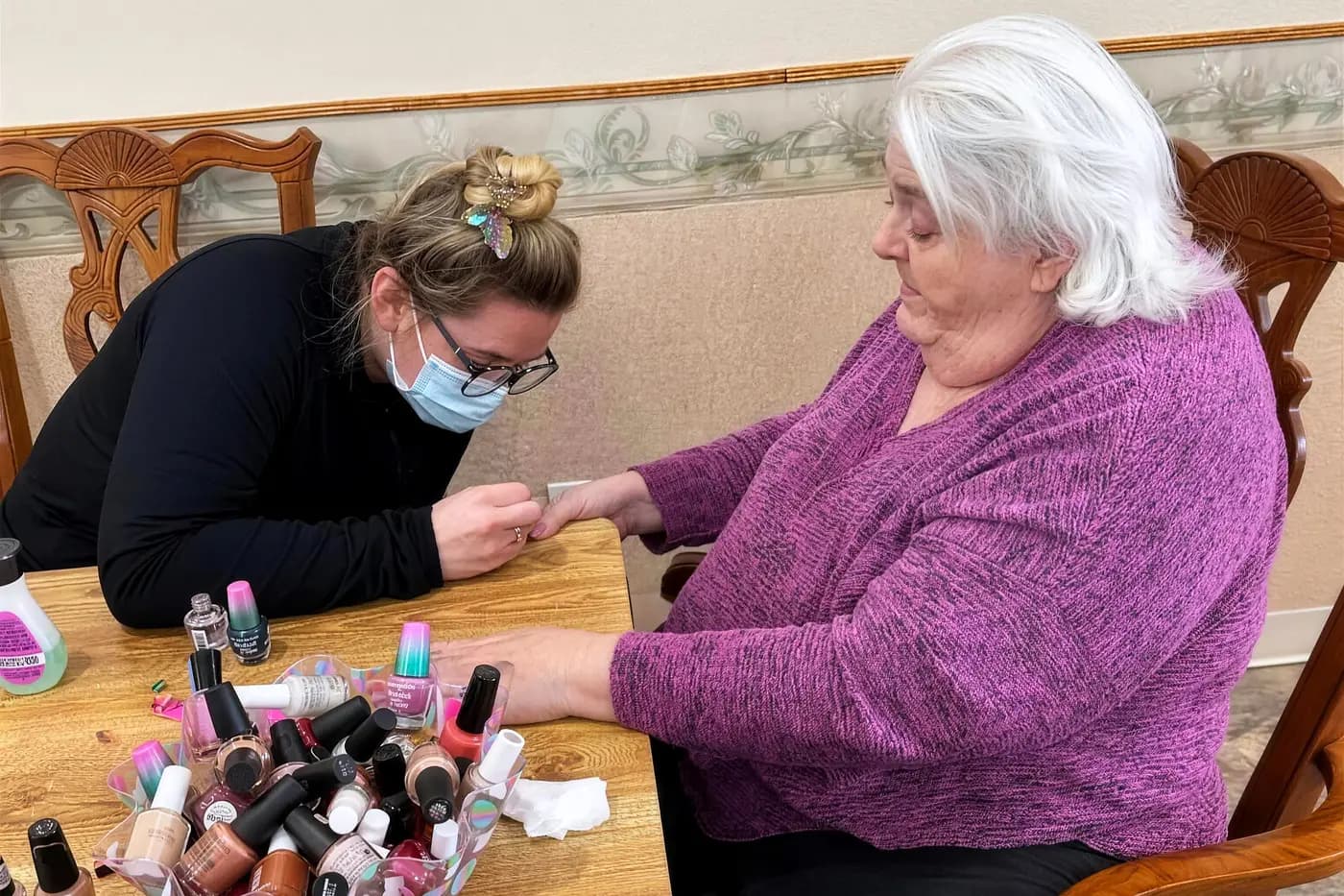 A resident having her nails painted at the dining table on nail day at Aspen Leaf